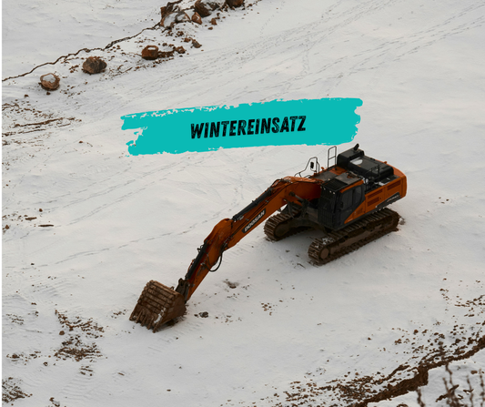Bagger arbeitet bei Schnee auf winterlicher Baustelle mit Frostschutzmaßnahmen